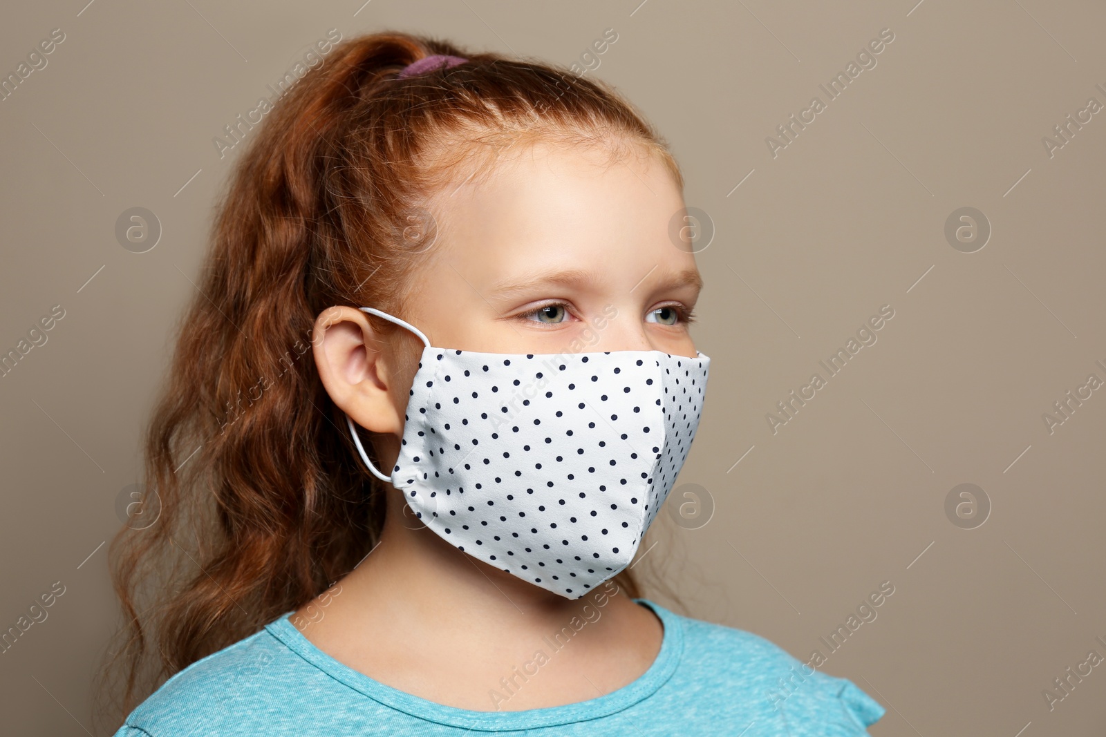 Photo of Preteen girl in protective face mask on brown background