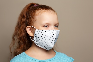 Preteen girl in protective face mask on brown background