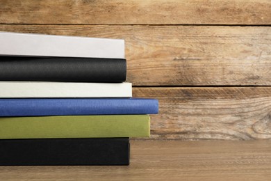 Stack of hardcover books on wooden table, space for text
