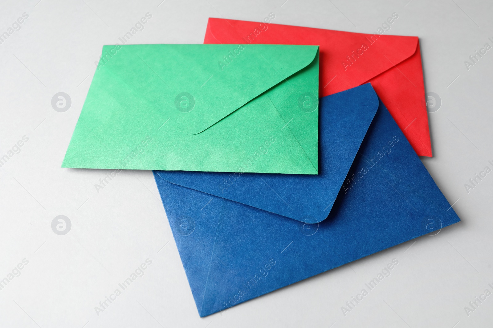 Photo of Colorful paper envelopes on light grey background. Mail service