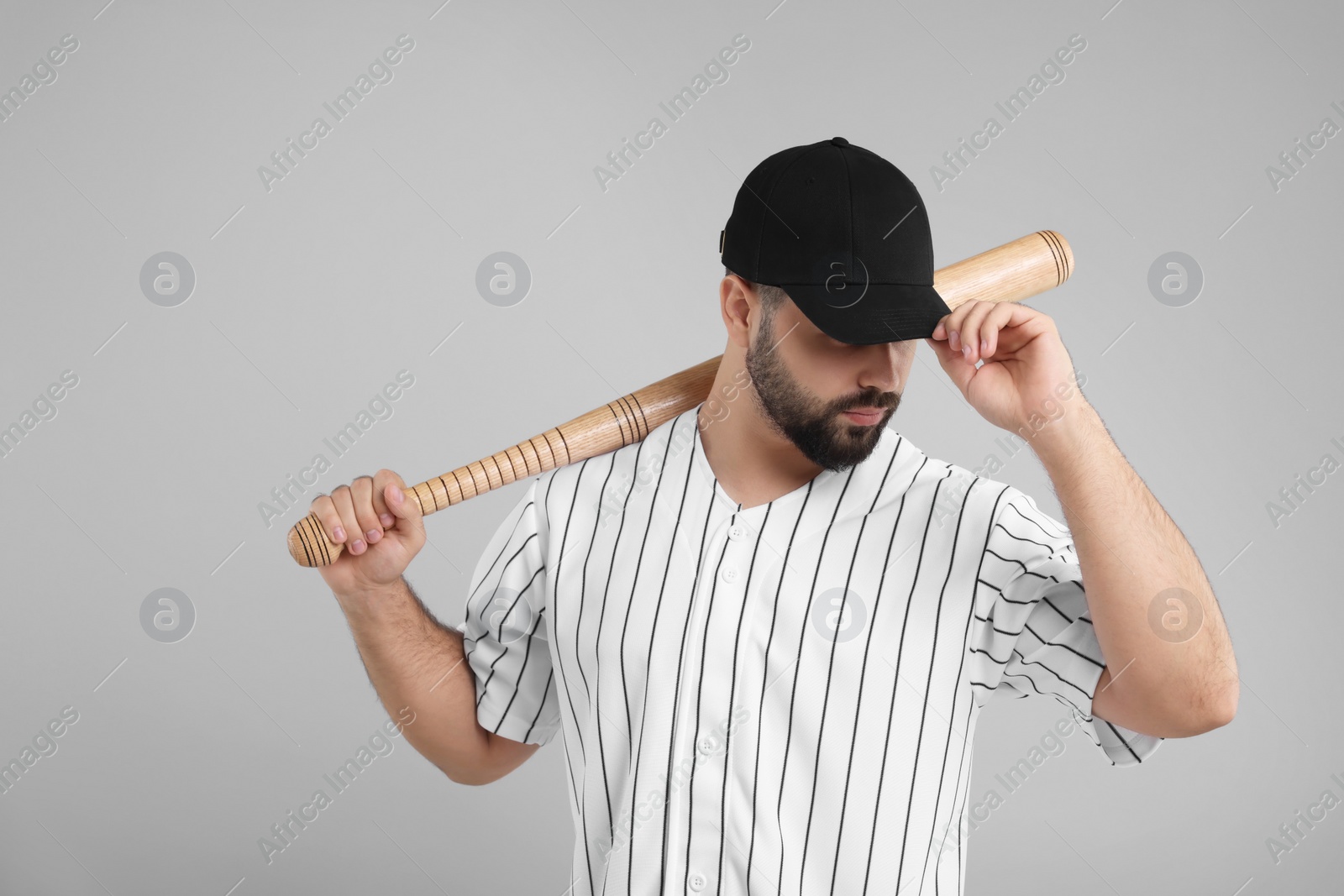 Photo of Man in stylish black baseball cap holding bat on light grey background