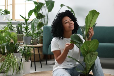 Photo of Relaxing atmosphere. Woman with ficus near another potted houseplants in room
