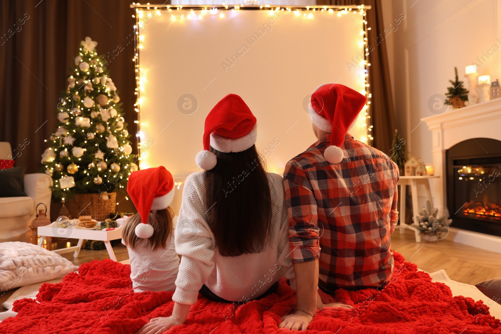 Photo of Family watching movie using video projector at home. Cozy Christmas atmosphere