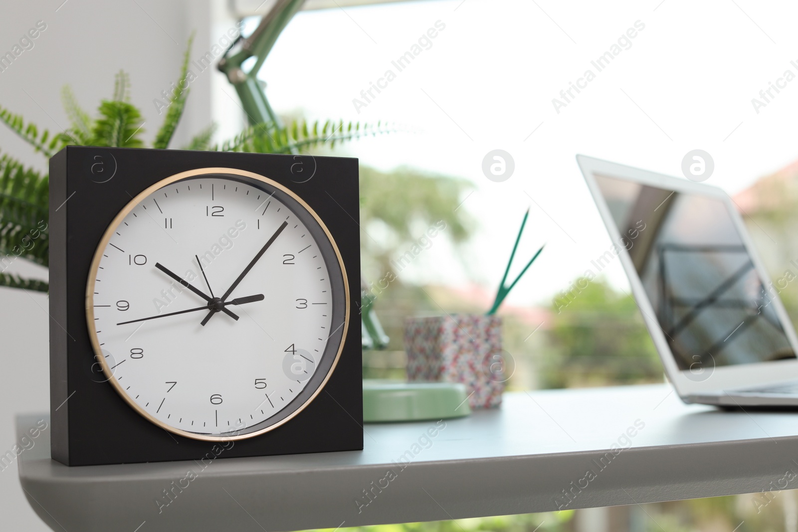 Photo of Analog clock on table in office. Time to work