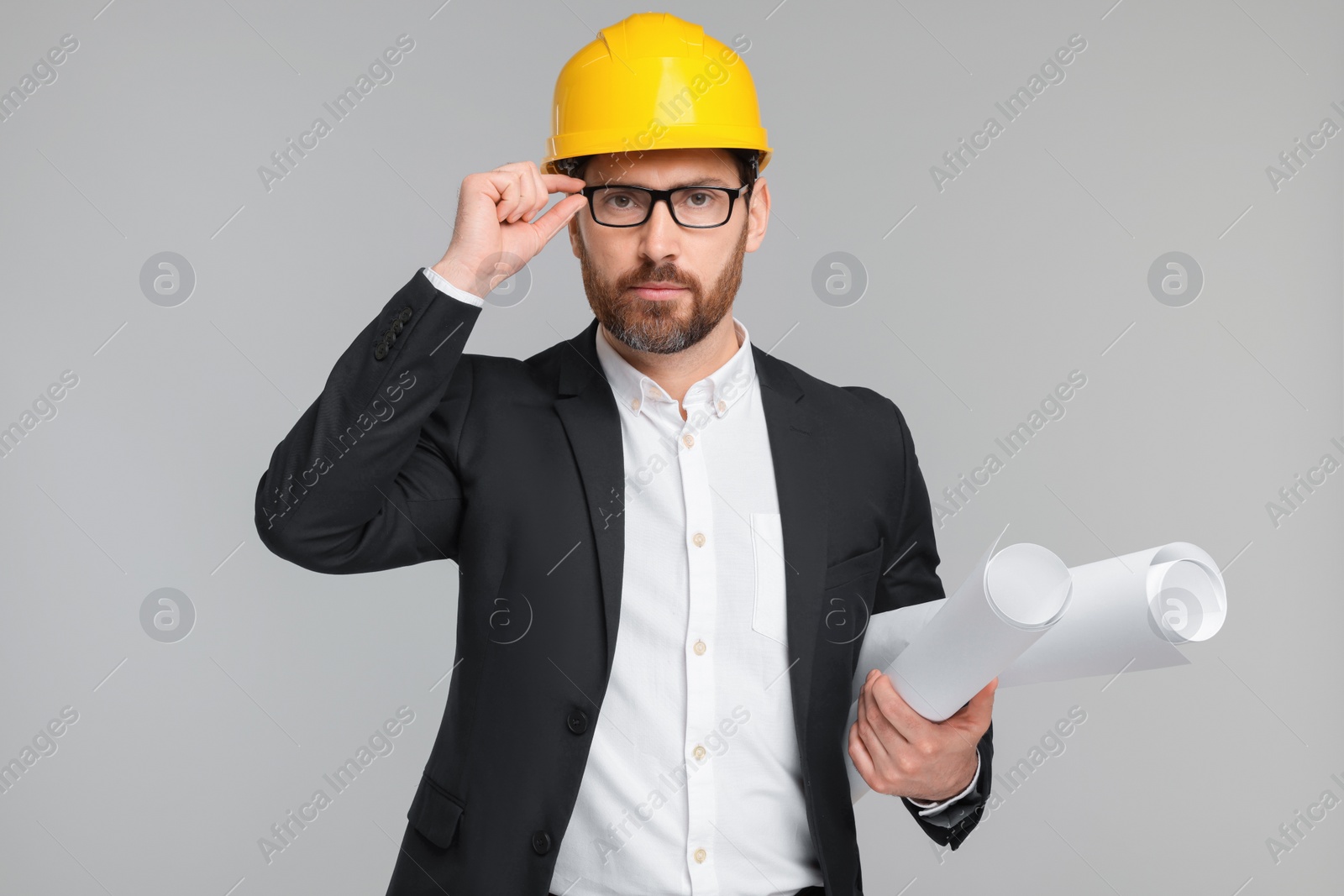 Photo of Architect in hard hat with drafts on gray background