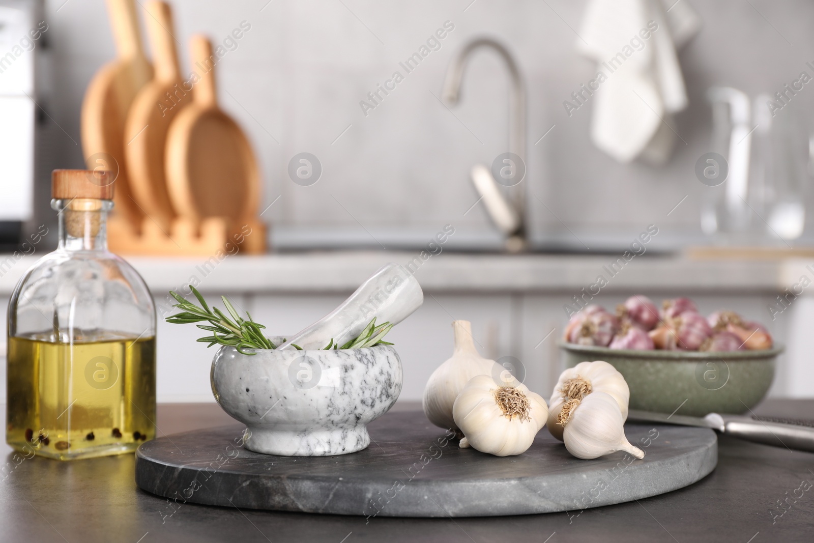 Photo of Fresh raw garlic, rosemary and oil on grey table