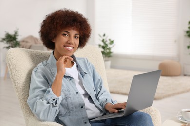 Photo of Young woman using modern laptop in room