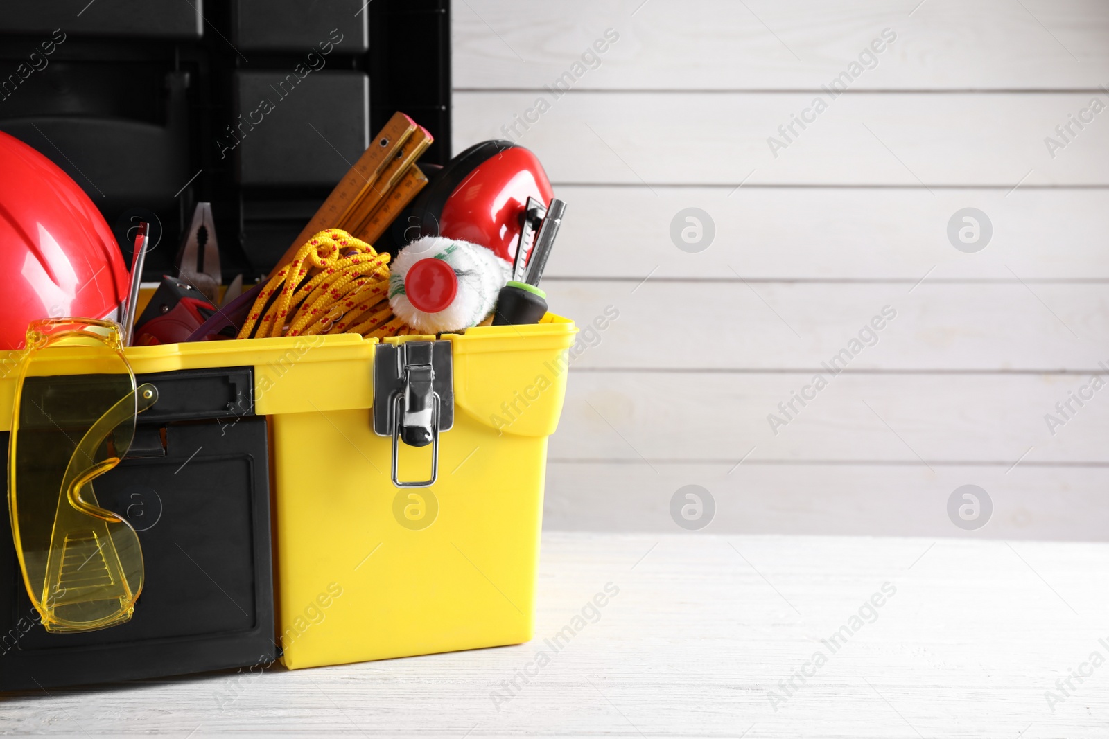 Photo of Plastic box with construction tools on wooden table. Space for text