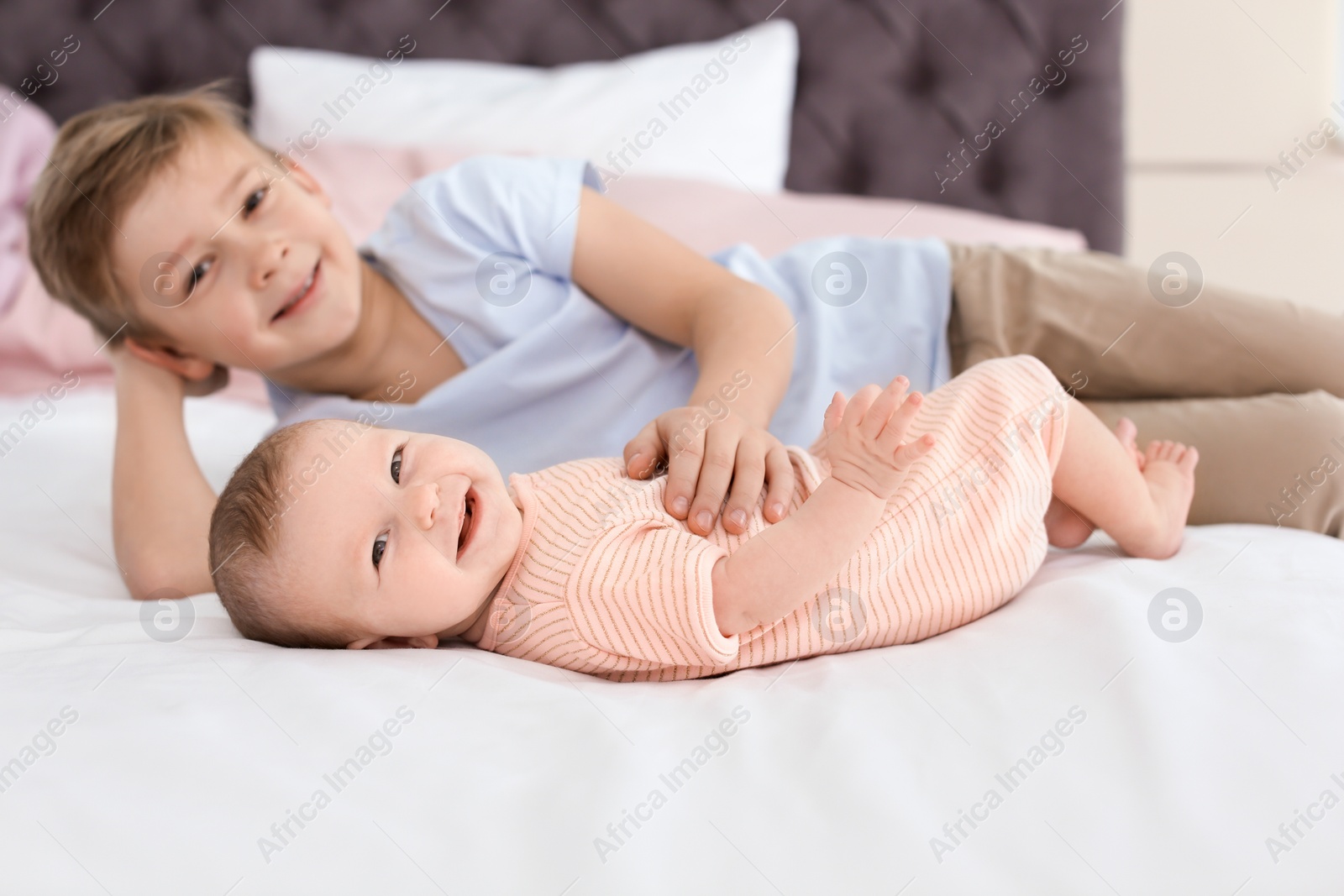 Photo of Cute little baby with elder brother lying on bed at home