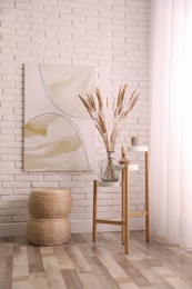 Photo of Fluffy reed plumes and painting in stylish room interior