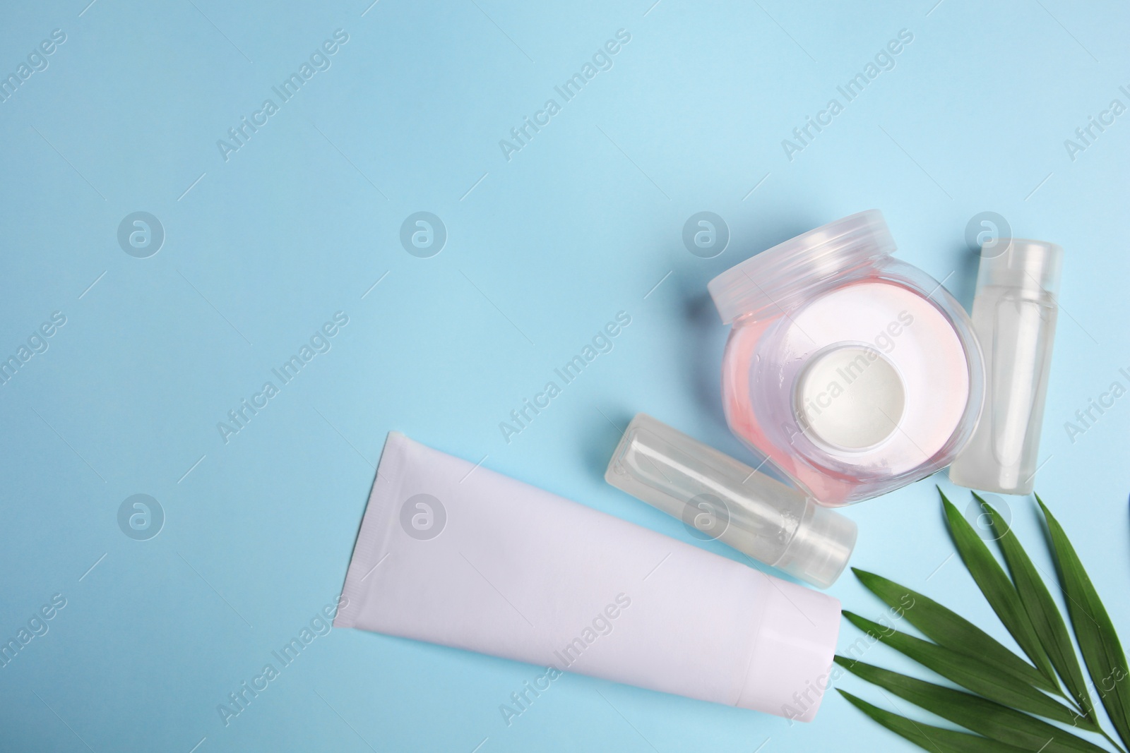 Photo of Cosmetic products and palm leaves on light blue background, flat lay. Space for text