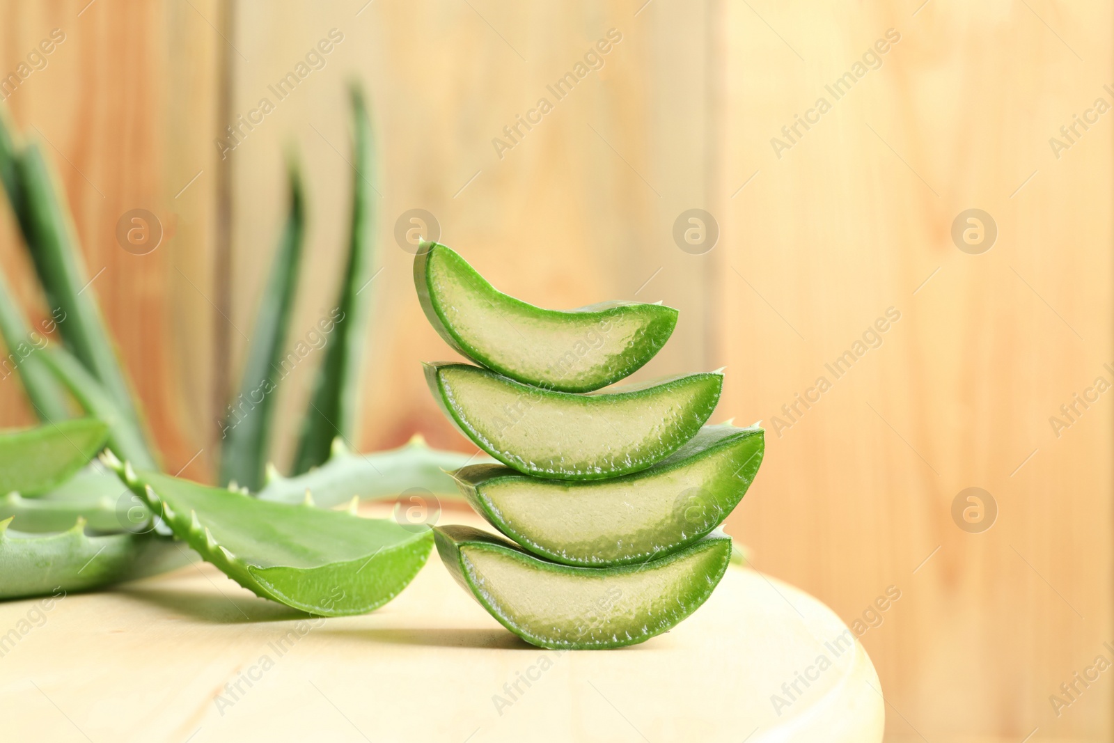 Photo of Fresh sliced aloe vera leaves on light table against wooden background