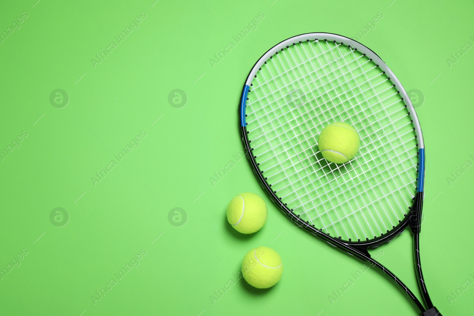 Photo of Tennis racket and balls on green background, flat lay. Space for text