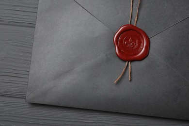 Photo of Envelope with wax seal on black wooden background, top view