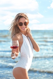 Photo of Young woman with glass of wine on beach