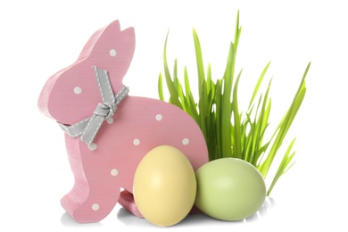 Cute wooden Easter bunny, grass and dyed eggs on white background