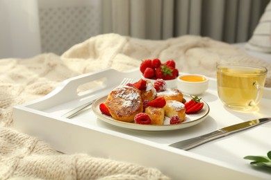 Tasty breakfast served in bedroom. Cottage cheese pancakes with fresh berries and icing sugar on wooden tray