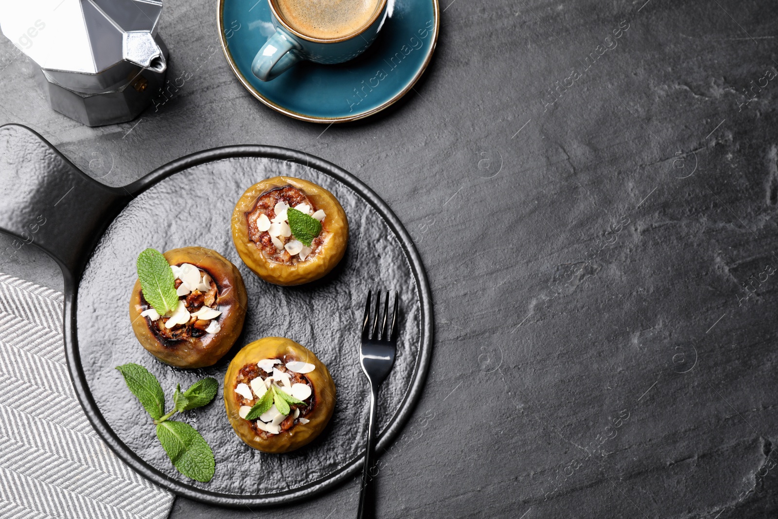 Photo of Delicious baked apples with nuts and mint served on black table, flat lay. Space for text