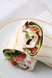 Delicious sandwich wraps with fresh vegetables on white plate, closeup