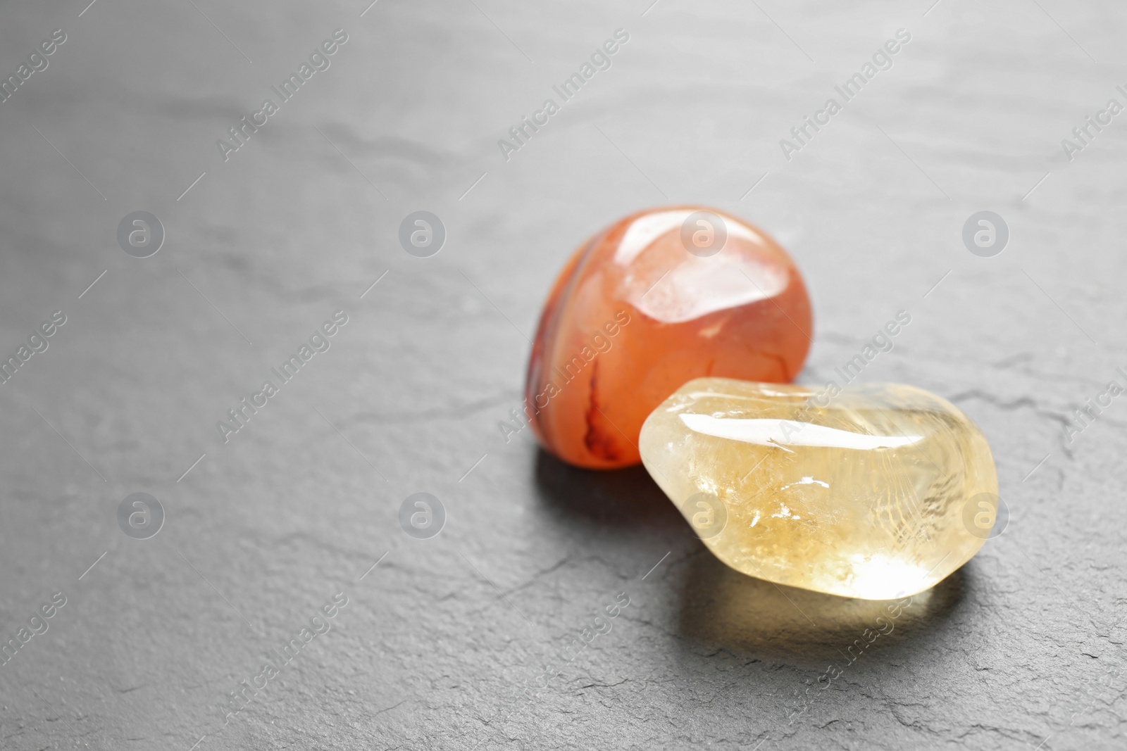 Photo of Orange gemstones on grey table, space for text