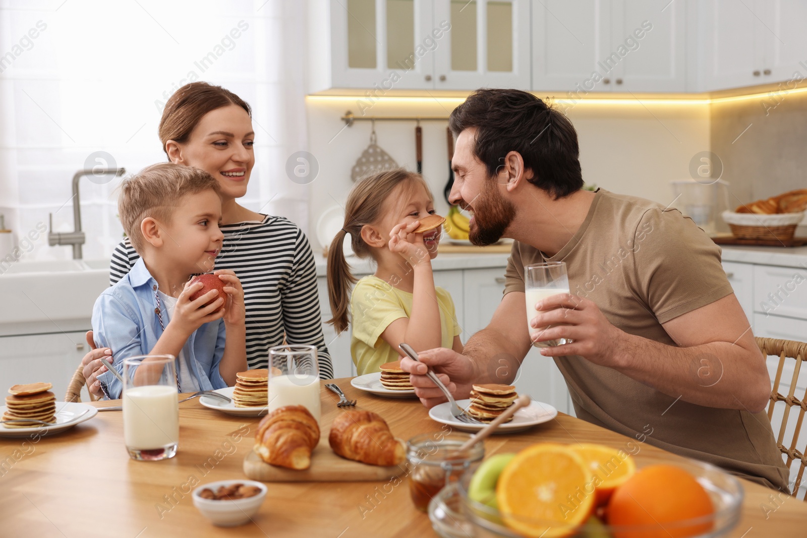 Photo of Happy family having fun during breakfast at table in kitchen