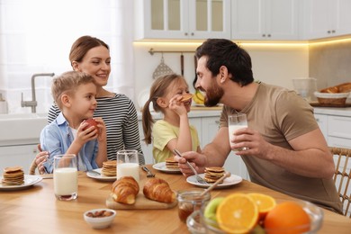 Photo of Happy family having fun during breakfast at table in kitchen