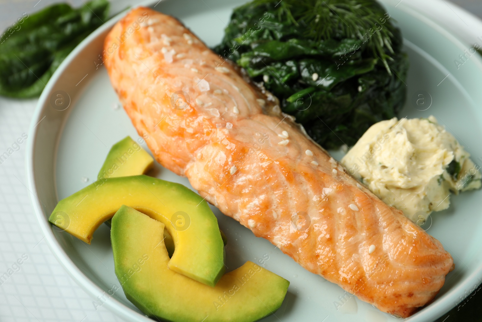 Photo of Tasty salmon with spinach and avocado on plate, closeup