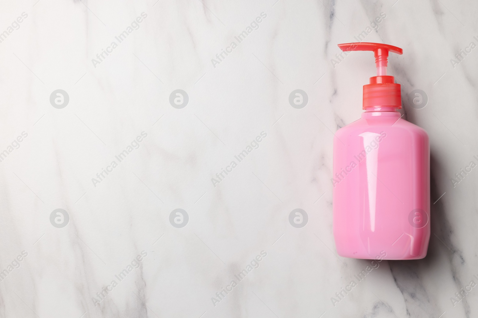 Photo of Dispenser of liquid soap on white marble table, top view. Space for text