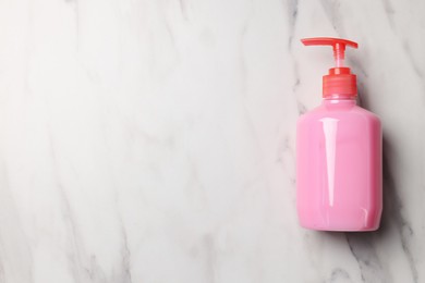 Dispenser of liquid soap on white marble table, top view. Space for text