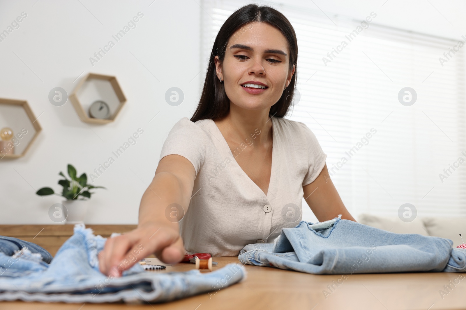 Photo of Young woman with jeans at wooden table indoors