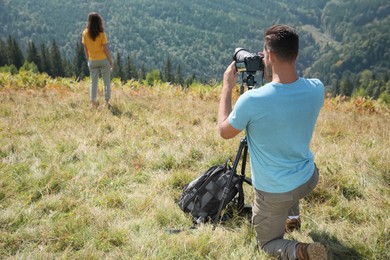 Photo of Professional photographer taking picture of woman in mountains, back view