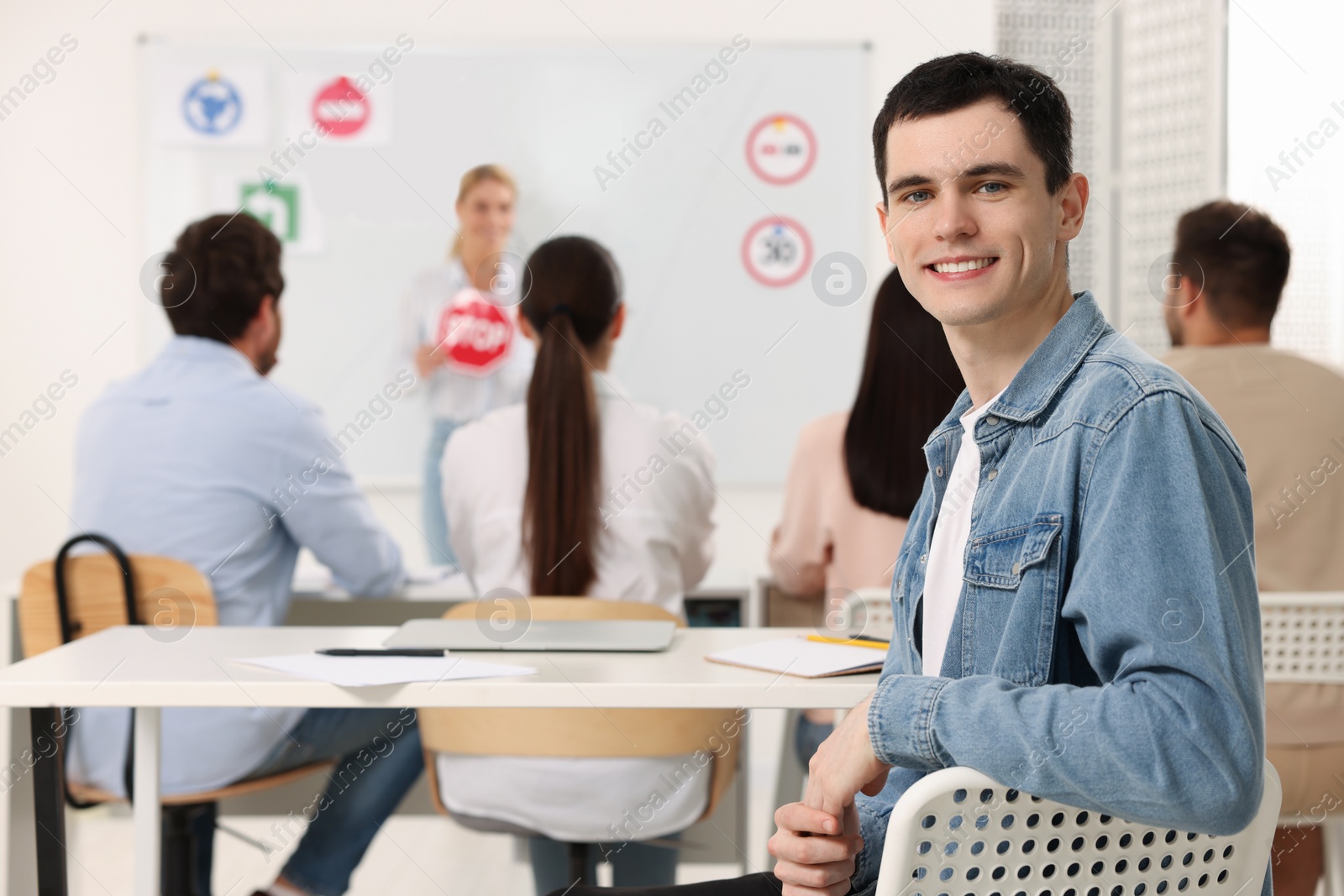 Photo of Happy man at desk in class during lesson in driving school