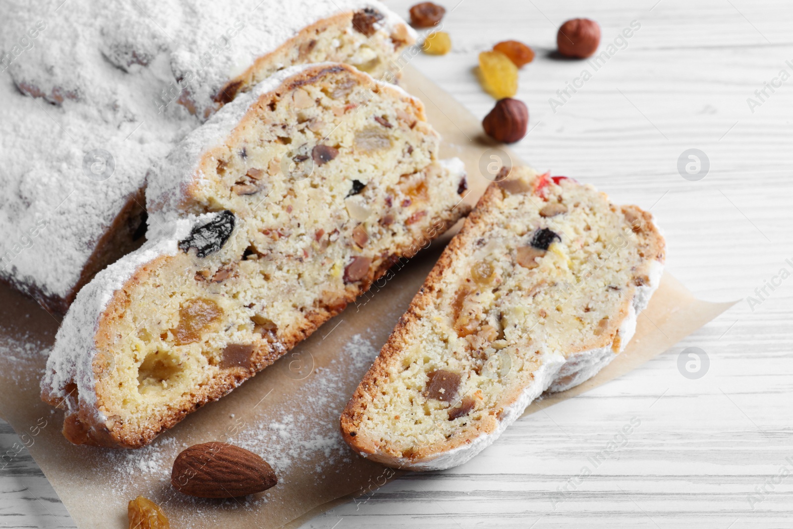 Photo of Traditional Christmas Stollen with icing sugar on white wooden table, closeup