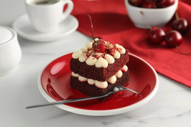 Piece of delicious red velvet cake and fork on white table, closeup