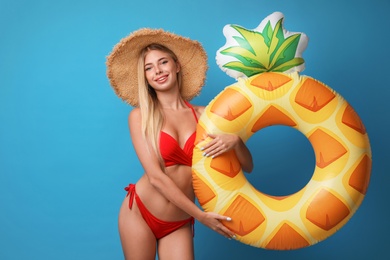 Photo of Pretty young woman wearing stylish bikini with inflatable ring on blue background