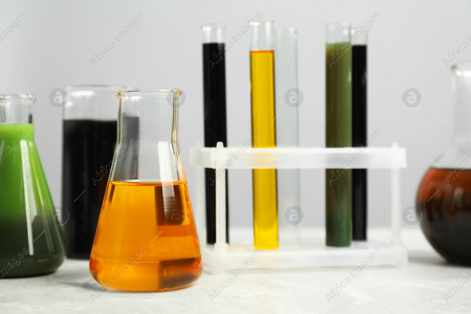 Photo of Laboratory glassware with different types of oil on white table, closeup