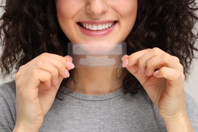 Photo of Young woman holding teeth whitening strips, closeup