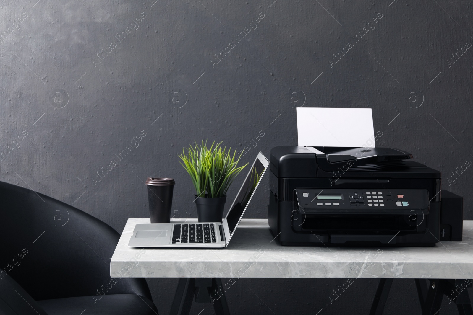 Photo of New modern printer, laptop and cup of drink on grey table indoors