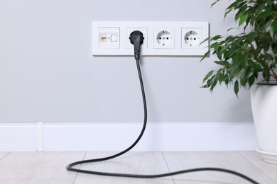 Power sockets and electric plug on grey wall