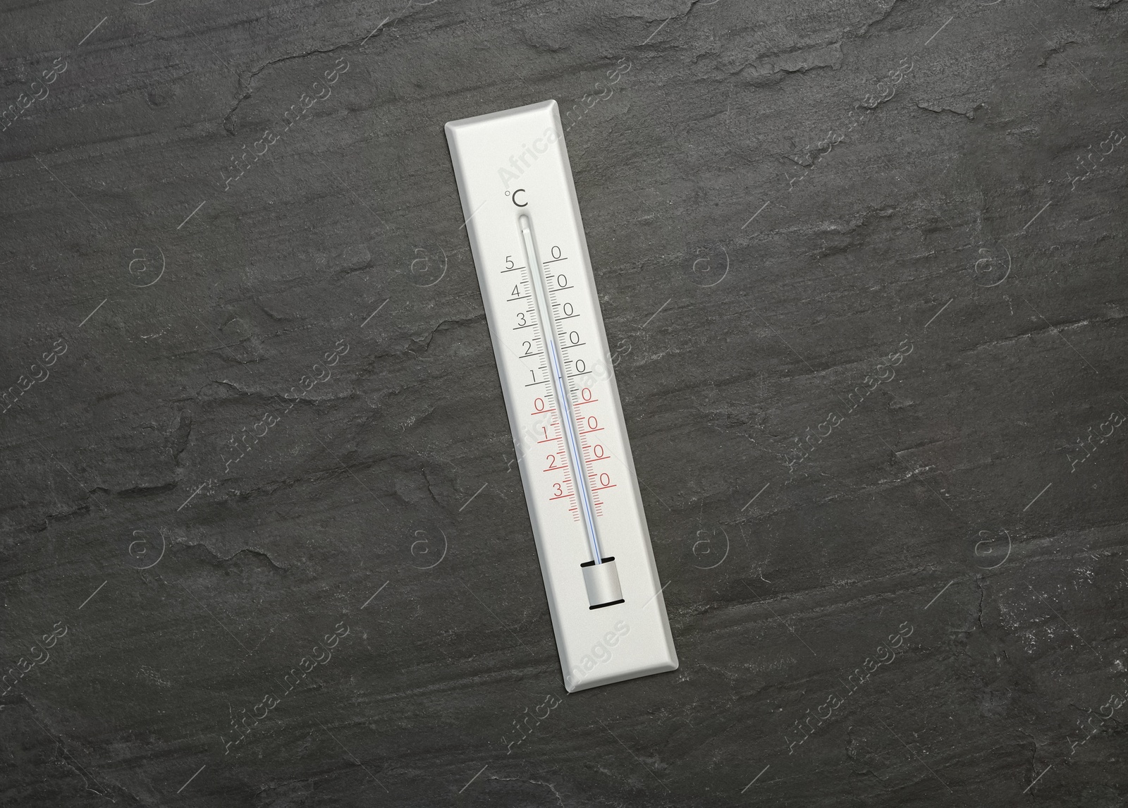 Photo of Weather thermometer on black slate background, top view