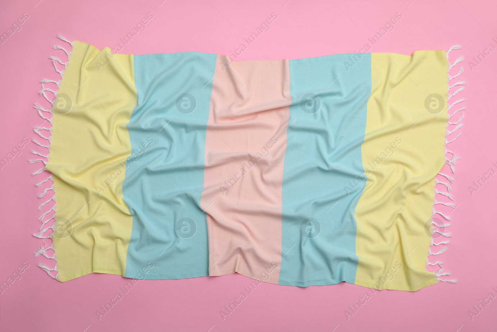 Photo of Crumpled striped beach towel on pink background, top view