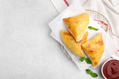 Photo of Delicious samosas with basil and tomato sauce on white table, flat lay. Space for text
