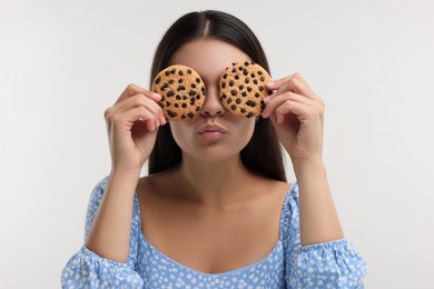 Photo of Young woman with chocolate chip cookies on white background