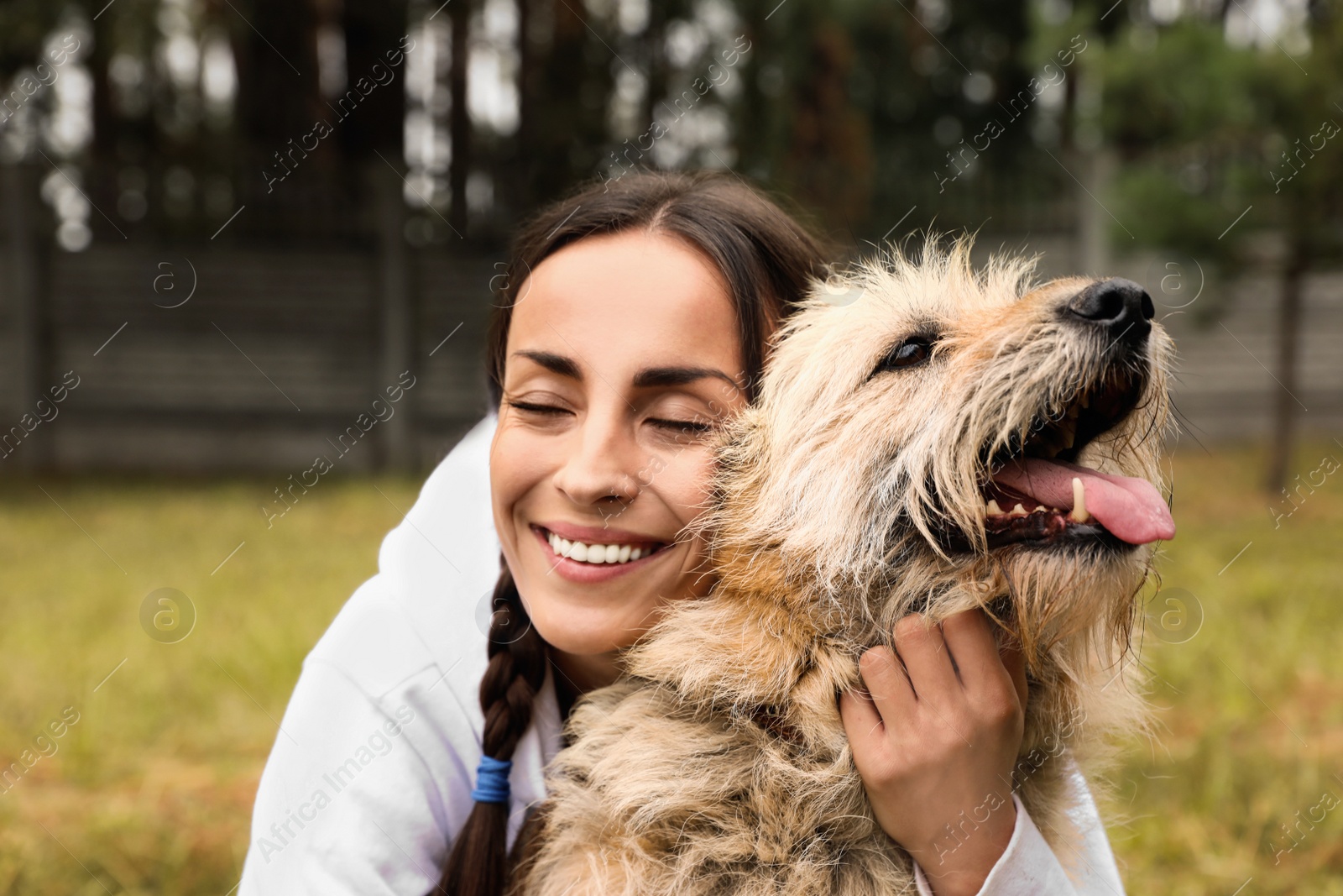 Photo of Female volunteer with homeless dog at animal shelter outdoors