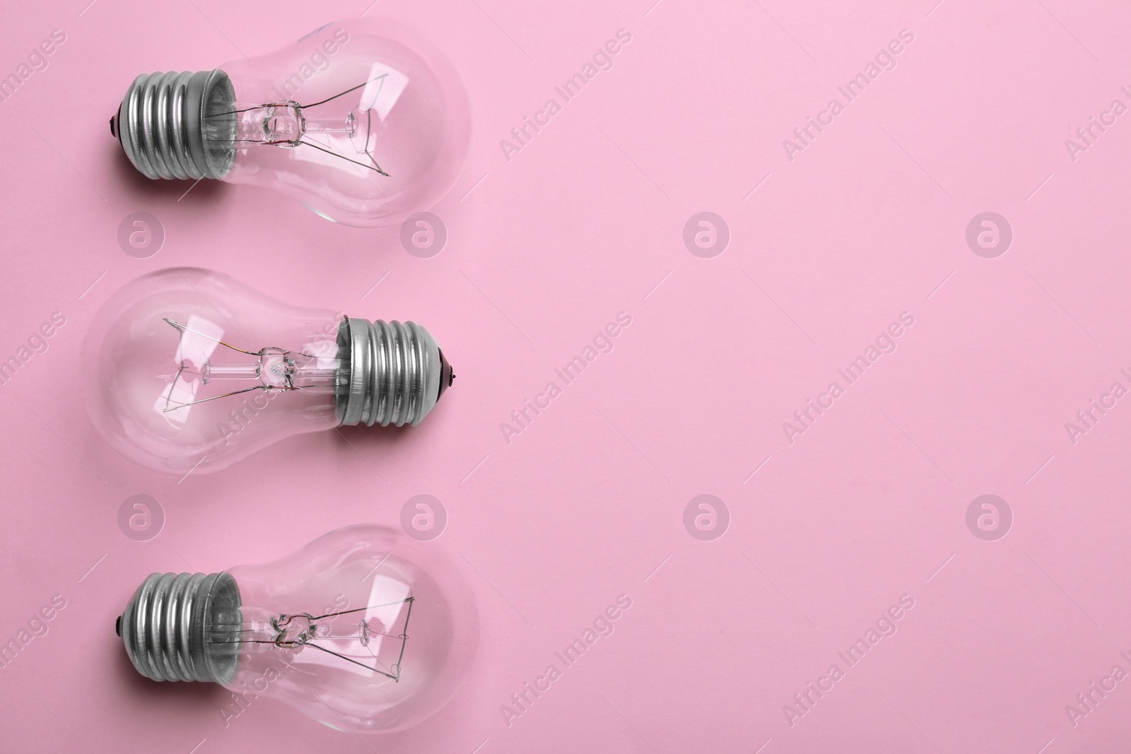 Photo of New incandescent lamp bulbs on pink background, top view. Space for text