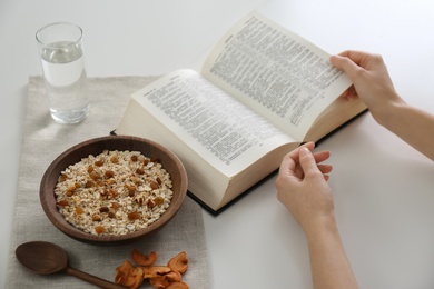 Woman with Bible having dinner at home, closeup. Great Lent season