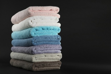 Photo of Different fresh soft terry towels on dark background