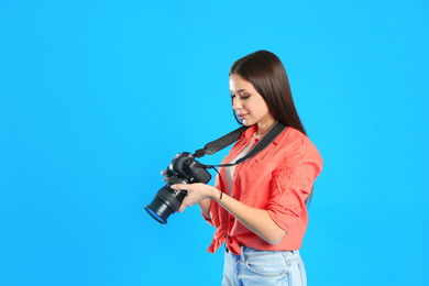 Photo of Professional photographer working on light blue background in studio. Space for text