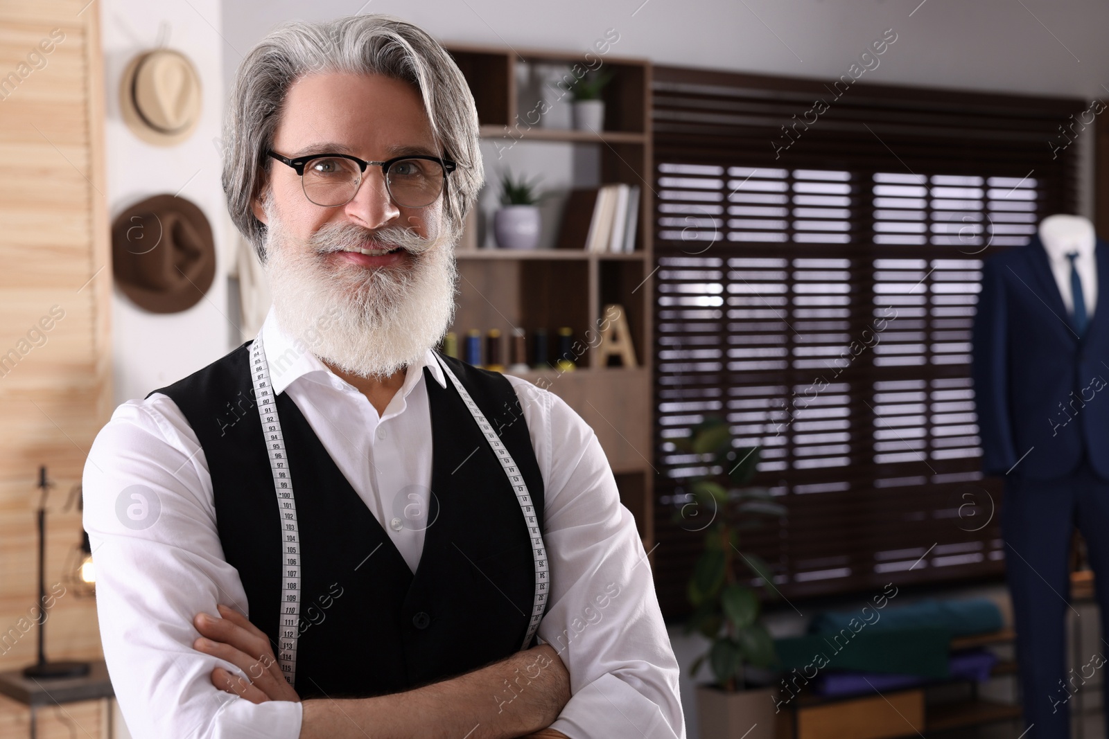 Photo of Professional tailor with measuring tape in workshop, space for text