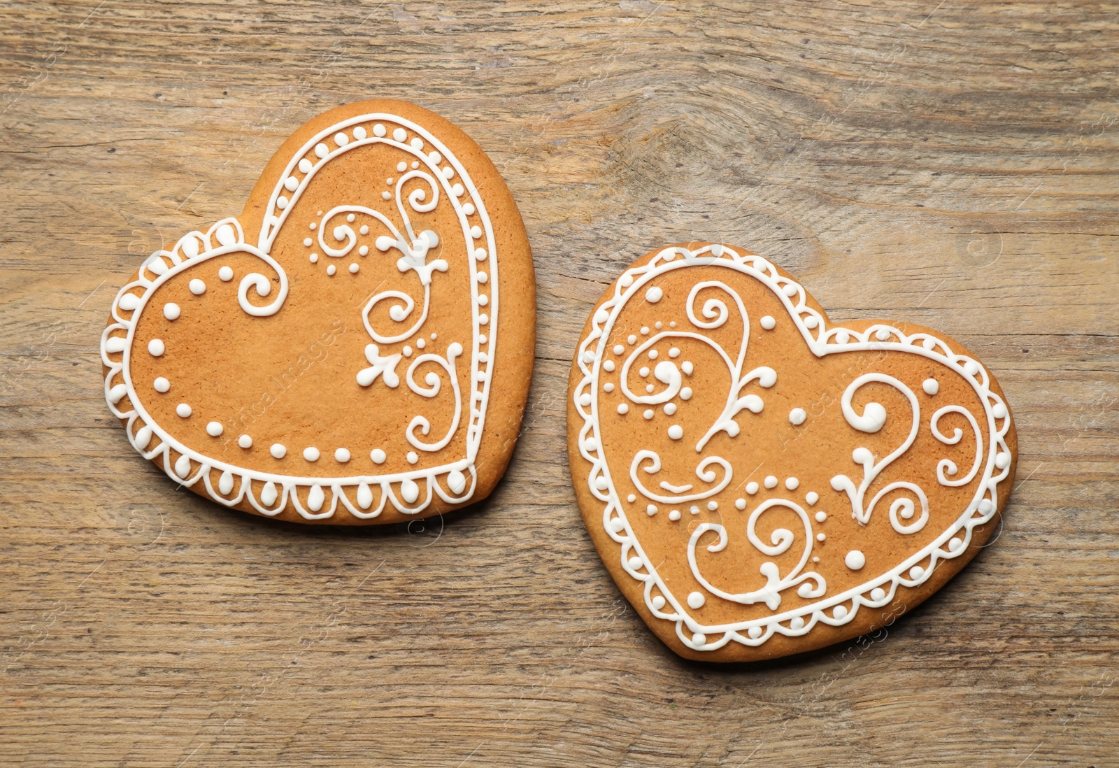 Photo of Decorated gingerbread hearts on wooden table, flat lay